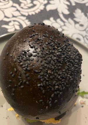 Una foto de Hamburguesa de Pasas y Piñones con Salsa Roquefort y Pan Negro …