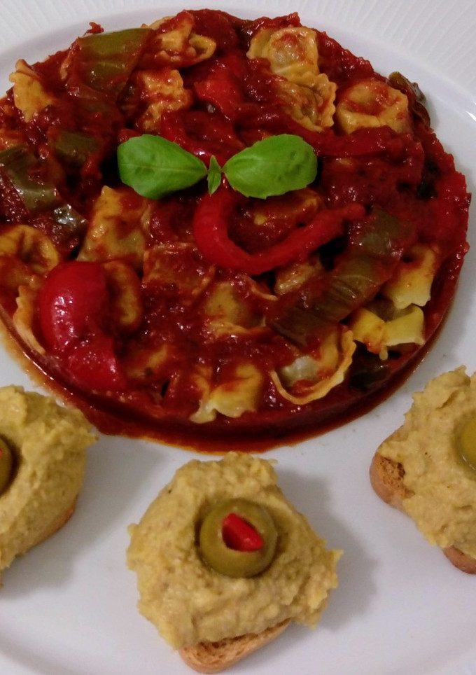 Una foto de Cappellettis de jamón con salsa de tomate y hummus con aceitunas