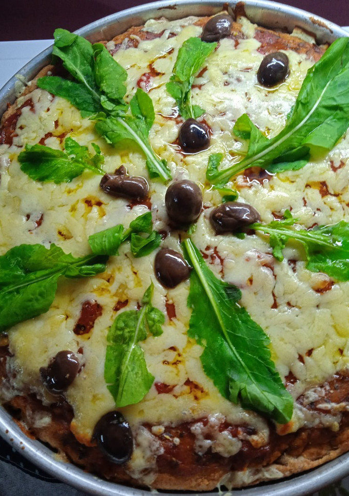 Una foto de Muzzarella integral con rúcula y aceitunas negras y parmesano🍕