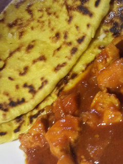 A picture of Butter naan with spicy chicken curry.