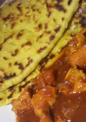 A picture of Butter naan with spicy chicken curry.