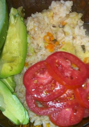 A picture of Carrot rice with avocado and fresh tomatoes.