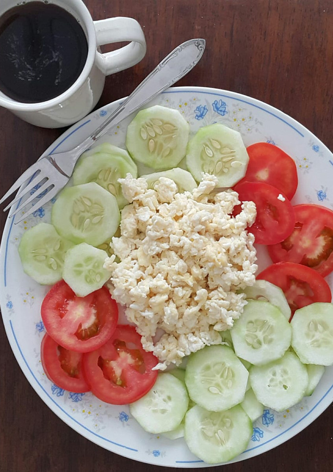 A picture of Scrambled eggs with tomato and cucumber salad.