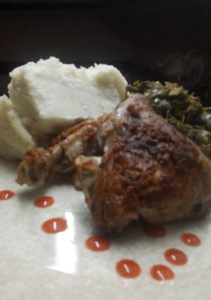 A picture of Fry chicken with greens accompanied by ugali.