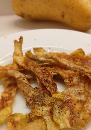 Una foto de Crujientes de Piel de Patata Asada al Aroma de AOVE y Pimienta Negra