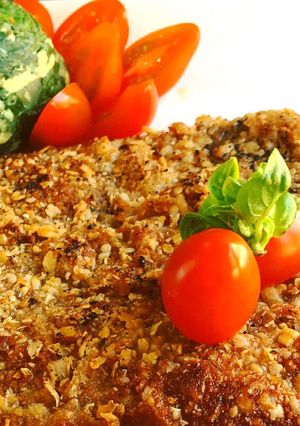 Una foto de Milanesas estilo peruanas a la chapa con buñuelos de acelga y tomates cherrys