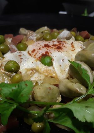 Una foto de Guisantes y habitas con jamón y huevos escalfados