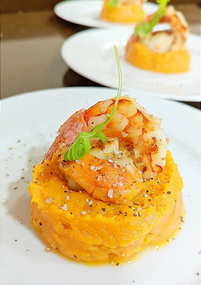 Una foto de Vieiras y gambas sobre puré de boniatos con salsa de whisky