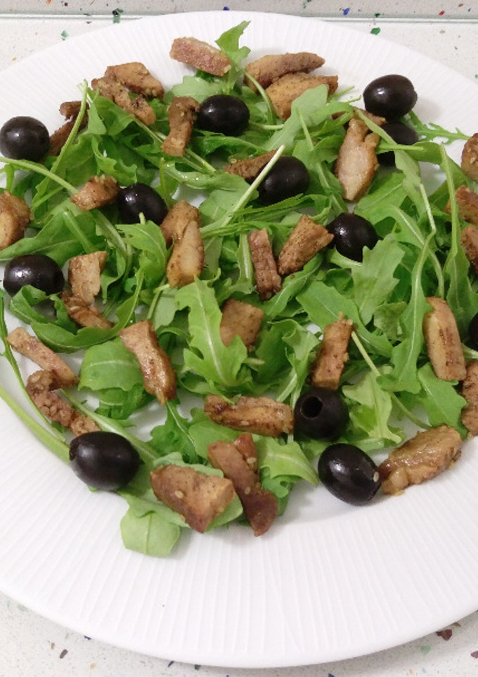 Una foto de Ensalada templada de rúcula con pechuga salteada y aceitunas