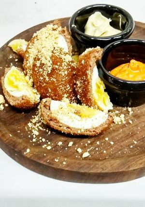 A picture of Scotch eggs with cocktail dip and cilantro peanut dip.