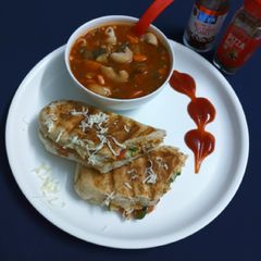A picture of Veg panini sandwich and minestrone soup.