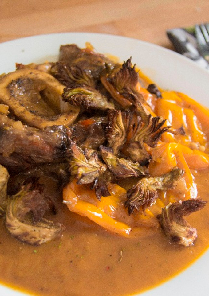 Una foto de Ossobuco guisado con chips de alcachofa