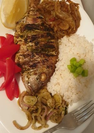 Una foto de Pescado a la varilla con cebolla marinada y arroz