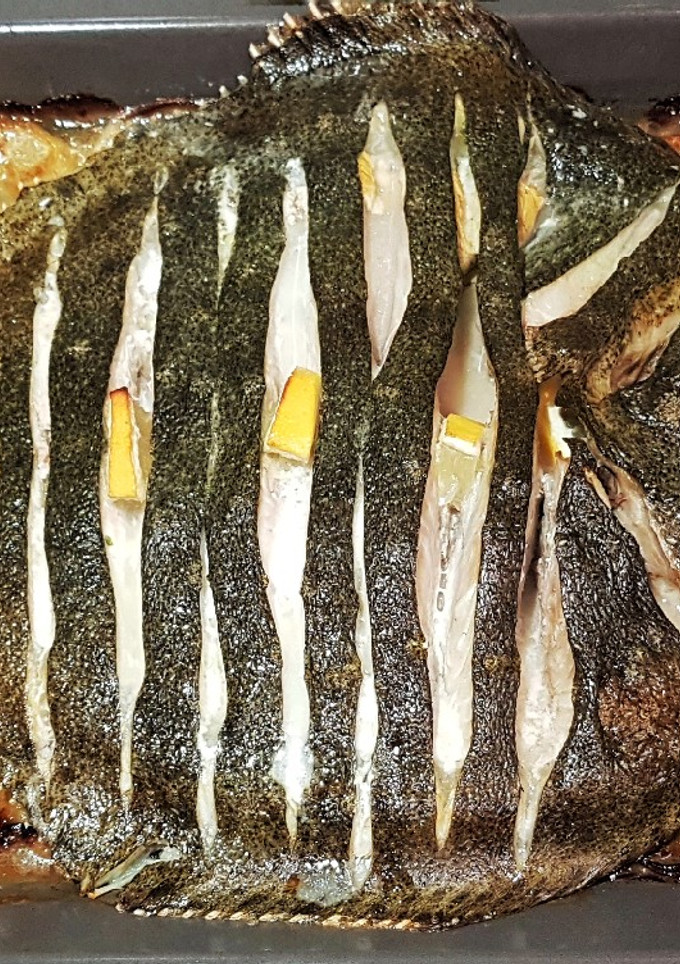 Una foto de Rodaballo salvaje al horno con guarnición de patatas y cebolla