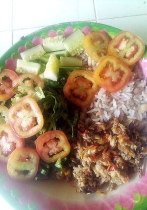 A picture of Rice and beans with vegetables and fish sauce.