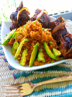 A picture of Nigeria jellof rice paired with avocado and chicken.