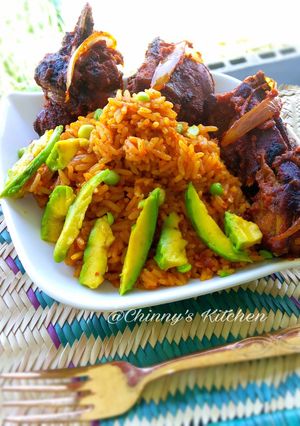 A picture of Nigeria jellof rice paired with avocado and chicken.
