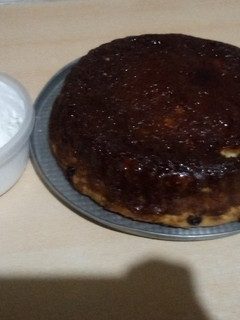 Una foto de Budín de pan con pasas de uva y caramelo acompañado de crema