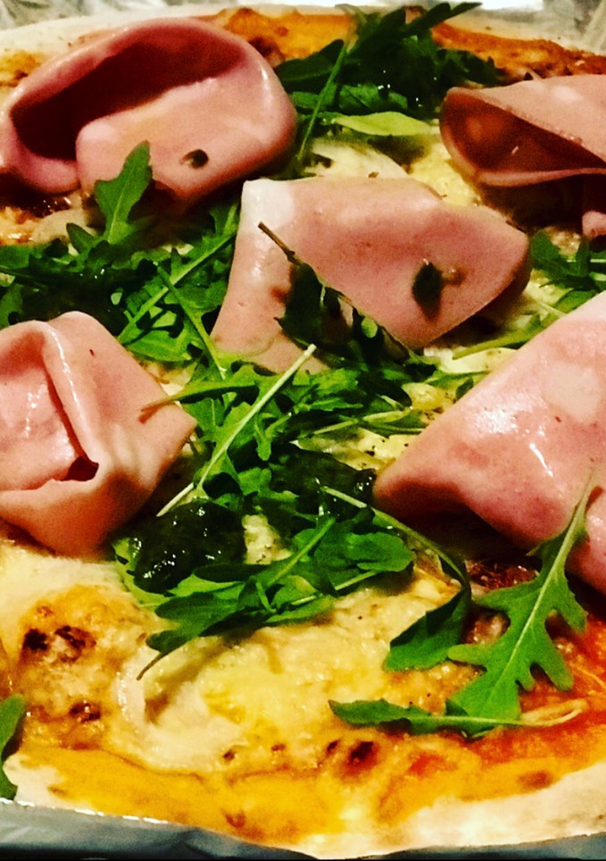 Una foto de Pizza casera de mortadela, rucula y concentrado de albahaca 🌿