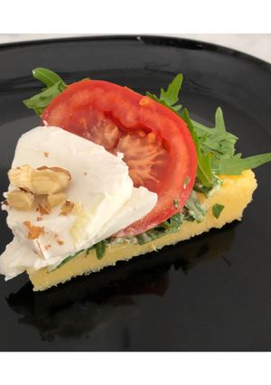 A picture of Savory Polenta Tart with Pesto, Ricotta, Arugula, Tomatoes, Mozzarella, and Walnuts.