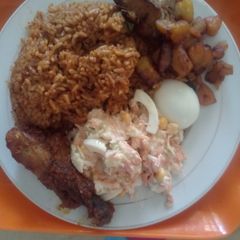 A picture of Coconut Jollof Rice with Cole slaw and other side attraction.
