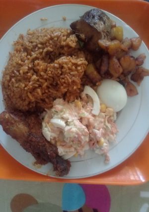 A picture of Coconut Jollof Rice with Cole slaw and other side attraction.