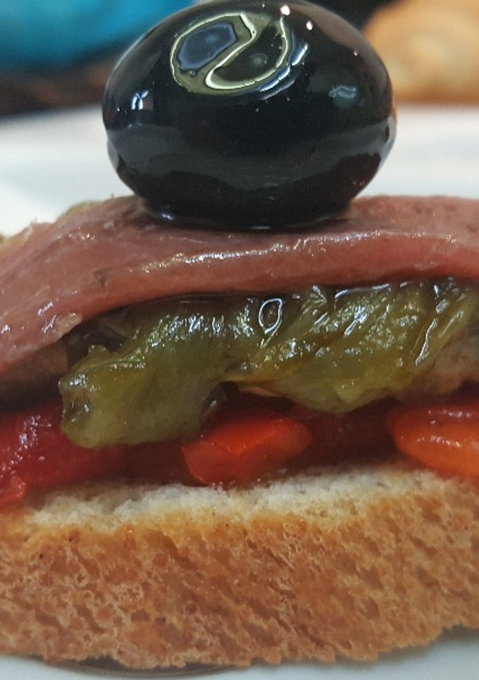 Una foto de Tostada de anchoas y pimientos rojos y verde