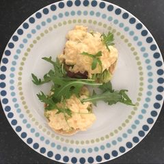 A picture of Scrambled egg and avocado on English muffin.