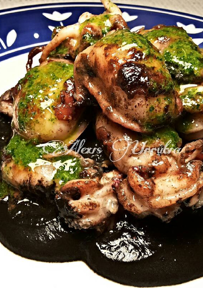 Una foto de Choquitos a la plancha en su tinta, con aceite de ajo y perejil