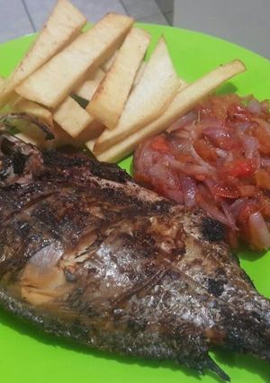 A picture of Roasted fish with yam chips and onion sauce.