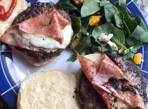 Una foto de Hamburguesas de cordero al yogurt, con ensalada de espinacas y queso por todos lados