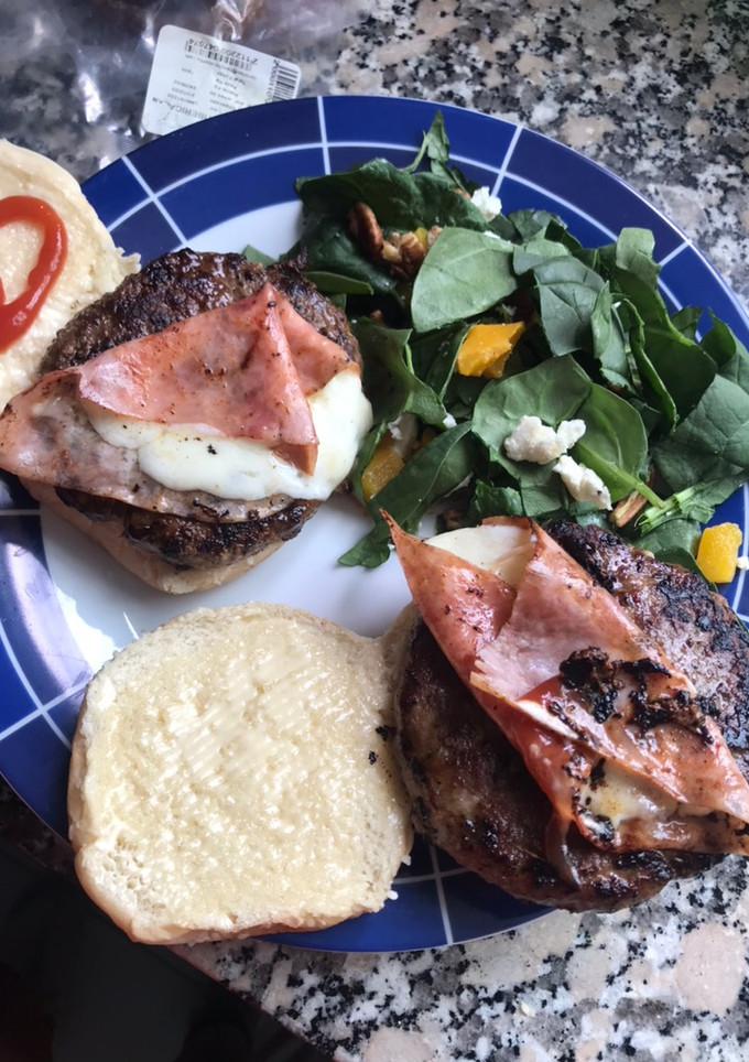 Una foto de Hamburguesas de cordero al yogurt, con ensalada de espinacas y queso por todos lados