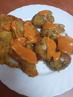 Una foto de Merluza frita con papas asadas y mojo de pimiento y tomate seco