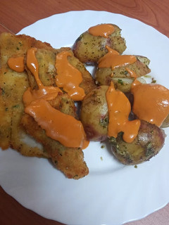 Una foto de Merluza frita con papas asadas y mojo de pimiento y tomate seco