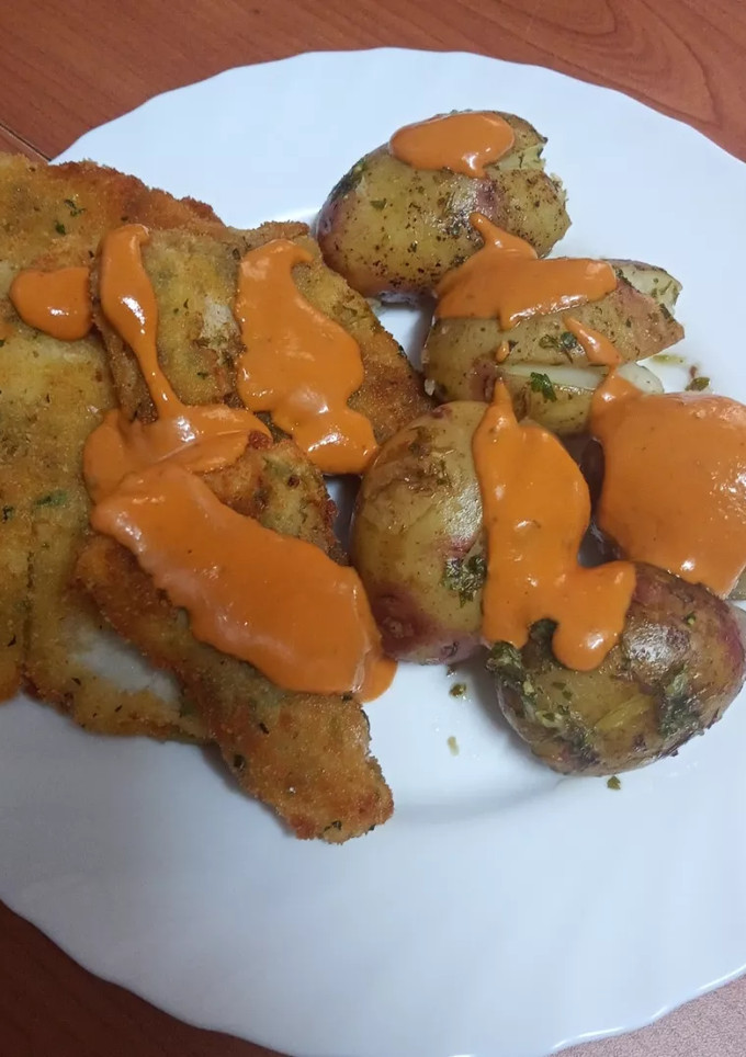Una foto de Merluza frita con papas asadas y mojo de pimiento y tomate seco