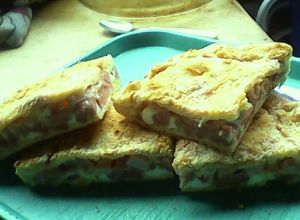Una foto de Pizza casera rellena con queso, fiambre, huevos y panchos