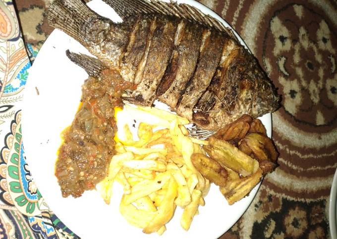 Fried tilapia fish with chips sauce and plantain