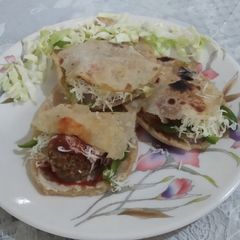 A picture of Pita bread with falafel and tahini sauce.