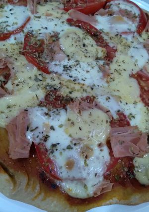 Una foto de Pizza semi integral, simple de tomate y quesitos