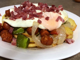 Cama de patatas fritas con verduras, chorizo y huevo frito con jamón