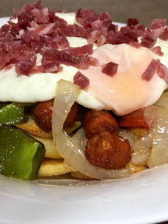Una foto de Cama de patatas fritas con verduras, chorizo y huevo frito con jamón