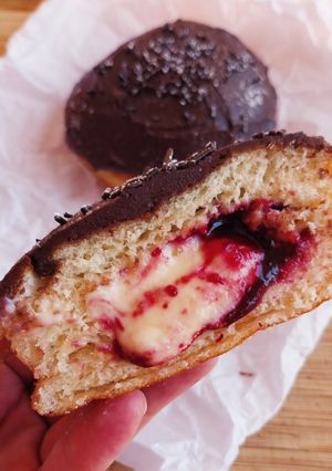 Una foto de Berlinas rellenas de crema y coulis de cerezas con ganache de chocolate