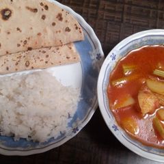 A picture of Drumstick and potatoes in red gravy.