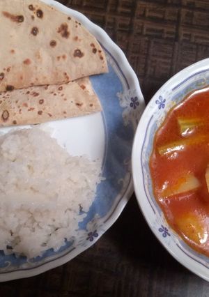 A picture of Drumstick and potatoes in red gravy.