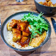 A picture of Crispy tofu top with sweet sticky and sour sauce with brown rice.