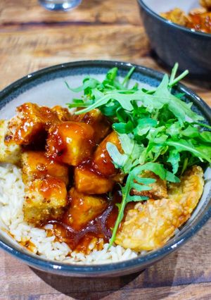A picture of Crispy tofu top with sweet sticky and sour sauce with brown rice.