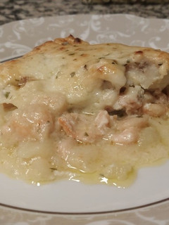 Una foto de Merluza al horno con salmón ahumado, gambas y patatas