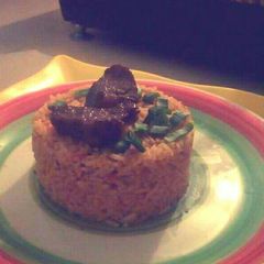 Jollof rice garnished with Beef and spring onions A picture of Jollof rice garnished with Beef and spring onions.