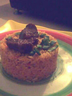 A picture of Jollof rice garnished with Beef and spring onions.
