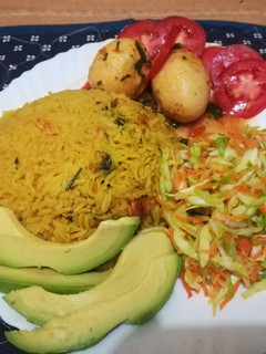A picture of Tumeric rice with sausages, egg curry and salad.